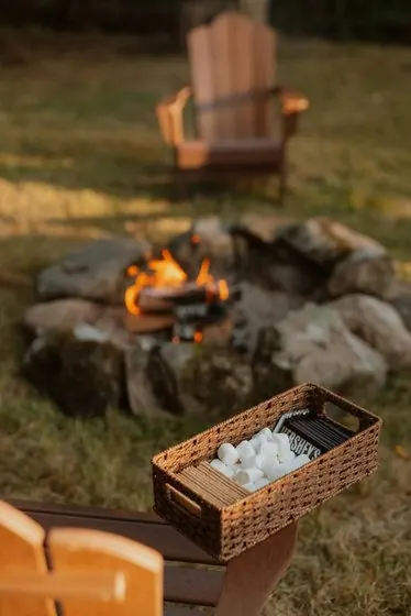 Campfire ringed with stones beside an Adirondack chair
